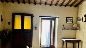 A room with a wooden door, a small table, a sofa, and a window with curtains.