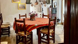 A dining area with a wooden table and chairs, a red and white striped tablecloth, and a hanging light fixture.
