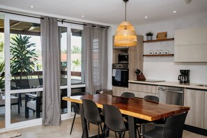 Una cocina moderna con una mesa de comedor de madera, sillas negras y una lámpara colgante.