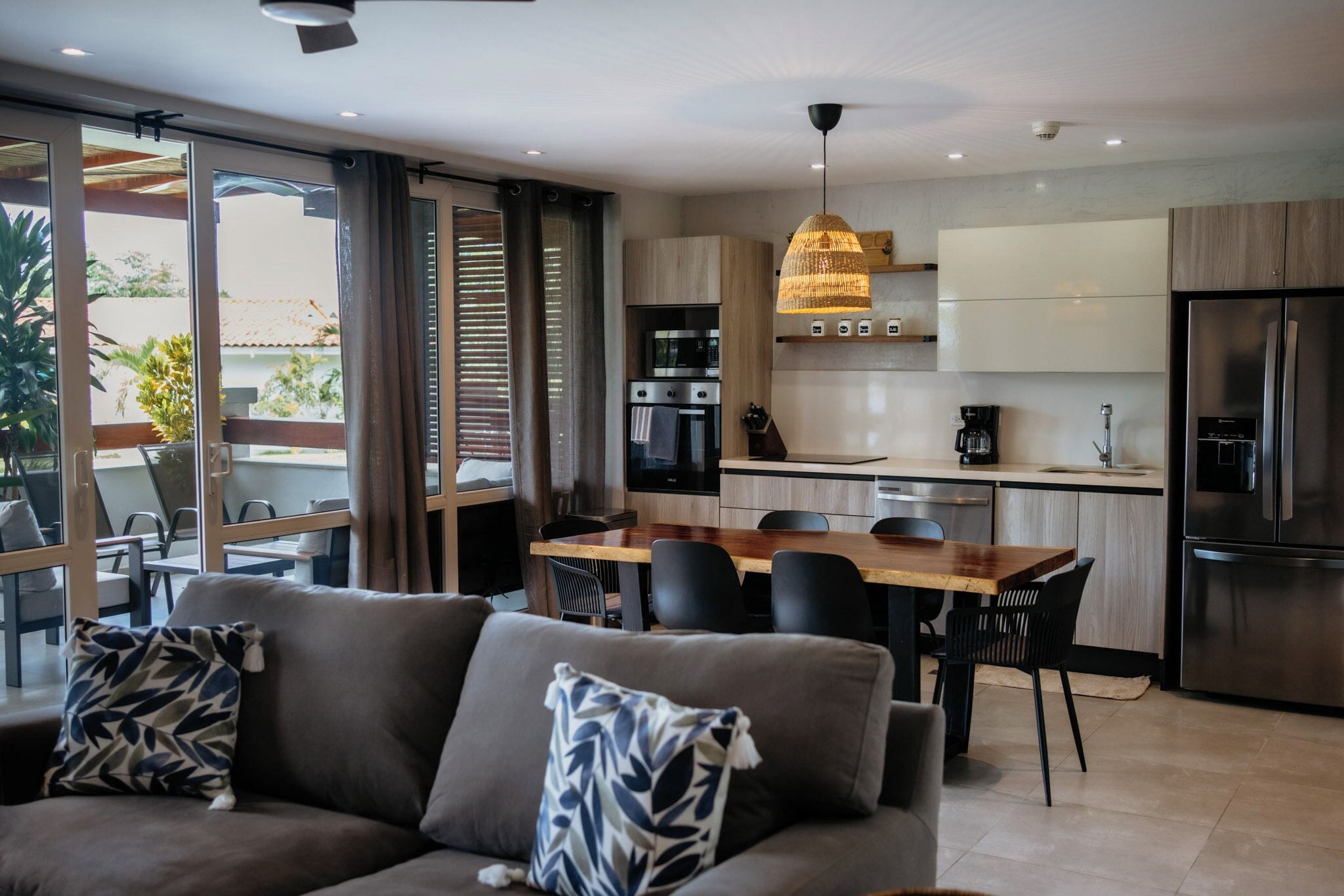 A modern kitchen with a dining area, featuring a sofa, chairs, and a coffee machine.