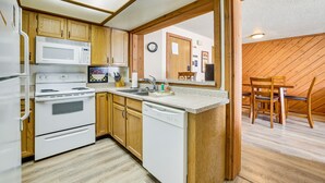 Une cuisine compacte dotée de meubles en bois, d’un four à micro-ondes, d’une cuisinière et d’un lave-vaisselle.