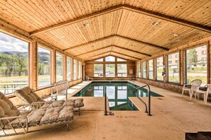 Ein Poolbereich mit Holzbalkendecke, großen Fenstern und Liegestühlen.