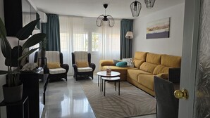 A living room with a sofa, two armchairs, a coffee table, and a potted plant.