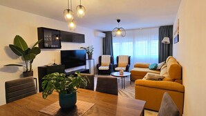 A modern living room with a TV, seating, and plants.