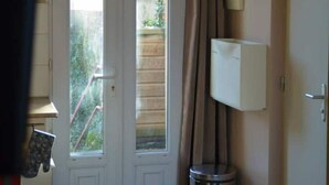 A hotel entrance with a double door, a trash bin, a lamp, and a small shelf with items.
