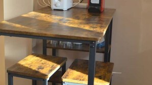 A small table with a toaster and a red appliance, possibly a coffee maker, on a wooden table with metal legs.