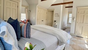A bedroom with a large bed, wooden beams, a ceiling fan, and a view of another room. - Bright, In-Town Nantucket Cottage + Yard - Walk to Main St. (Nantucket)