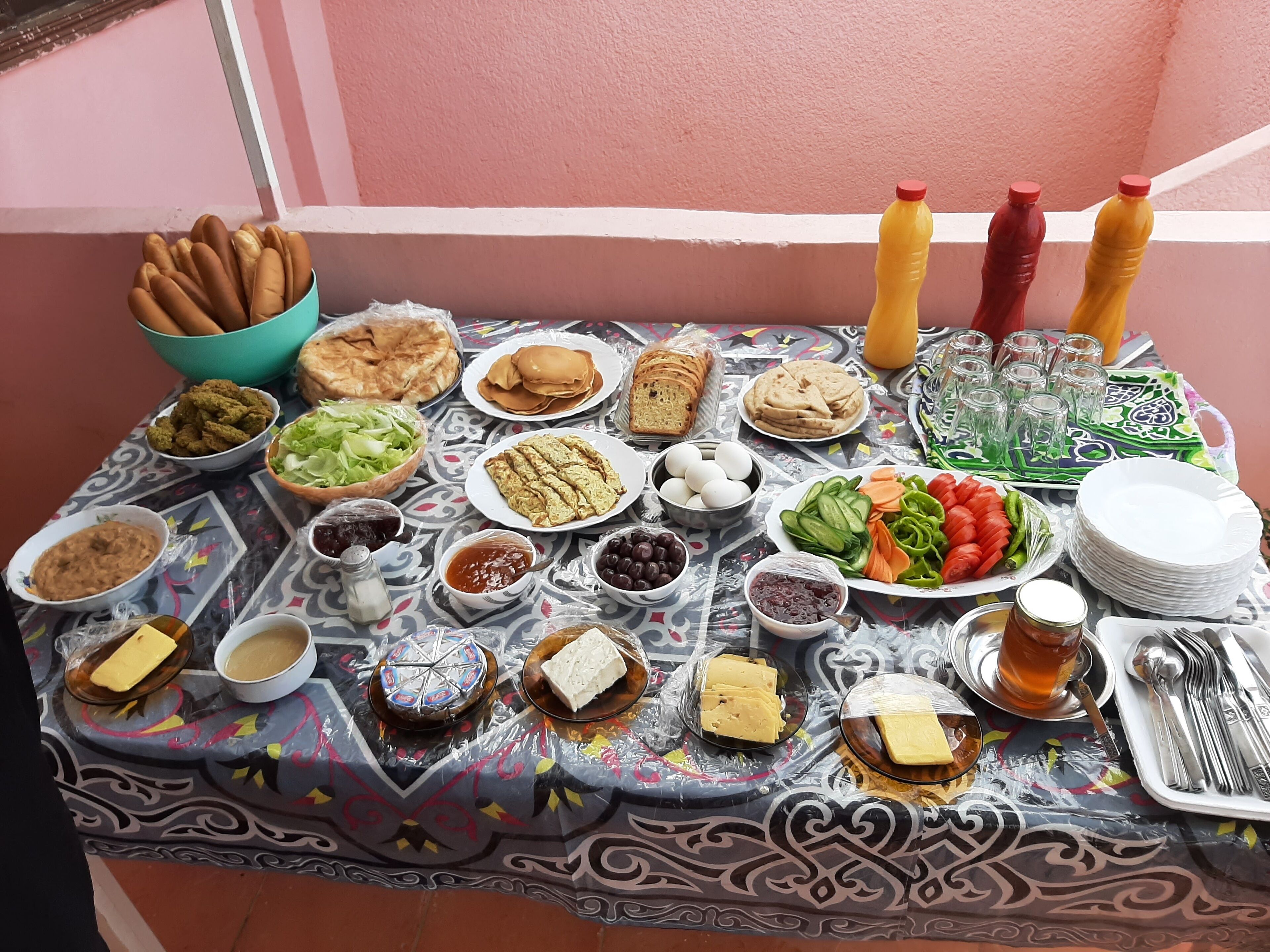 A table with various food items and condiments, including bread, eggs, vegetables, and drinks.