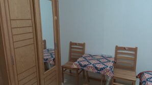A room with a wooden wardrobe, two wooden chairs, and a table with a patterned tablecloth. - Gohar Guest House (Giza)
