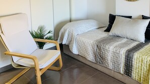 Ein modernes Schlafzimmer mit Bett, Stuhl, Wandspiegel und Deckenleuchte.