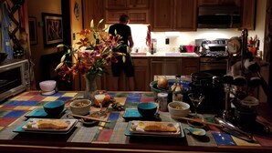 A kitchen with wooden cabinets, a microwave, a stove, and a person standing by the counter. - Peaceful, Private Woodland Lot, 5 miles to UNC/Downtown CH. Stay 3 days-3 months (Chapel Hill)