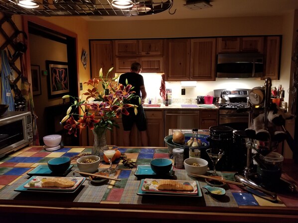 A kitchen with wooden cabinets, a microwave, a stove, and a person standing by the counter.