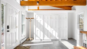 A spacious hallway with white doors, a wooden ceiling, and a patterned rug.