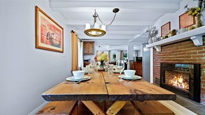 A dining area with a large wooden table, benches, and a fireplace.