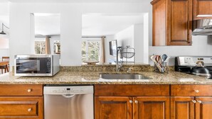 A modern kitchen with a built-in dishwasher, stainless steel appliances, and wooden cabinets.