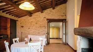 A rustic dining area with a brick wall, wooden beams, and a fireplace. - Villaluce Wine Agriturismo (Castiglione del Lago)
