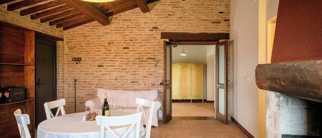 A rustic dining area with a brick wall, wooden beams, and a fireplace.