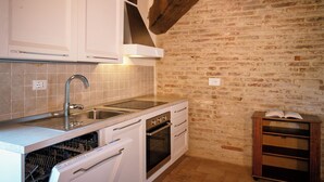 A kitchen with white cabinets, a stainless steel sink, a dishwasher, and an oven. - Villaluce Wine Agriturismo (Castiglione del Lago)