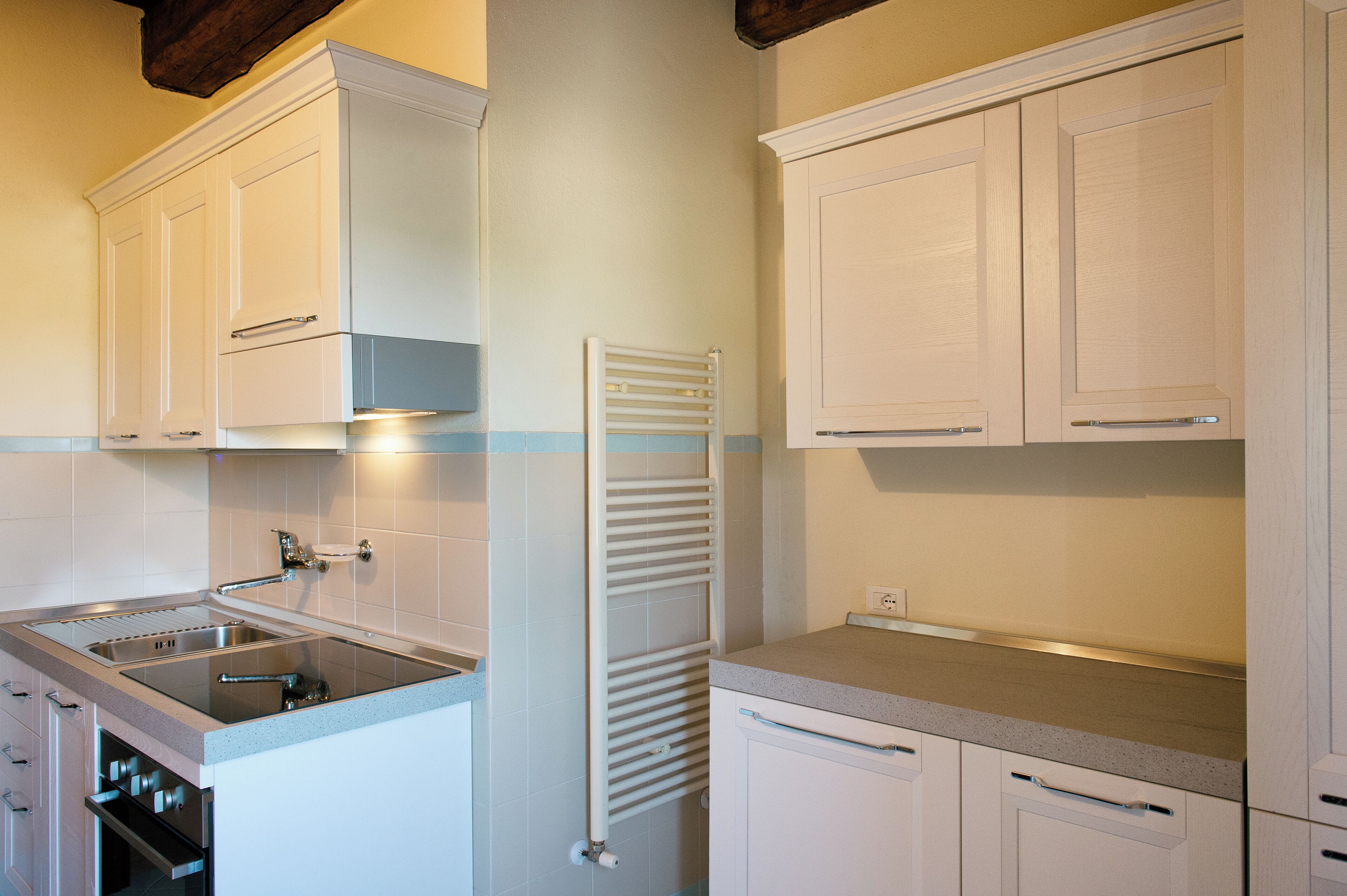 A kitchen with white cabinets, a double sink, and a built-in oven.