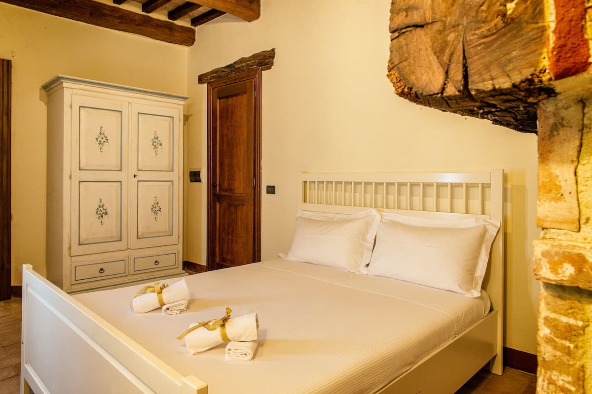 Une chambre à coucher avec un lit, une armoire et un mur en pierre.