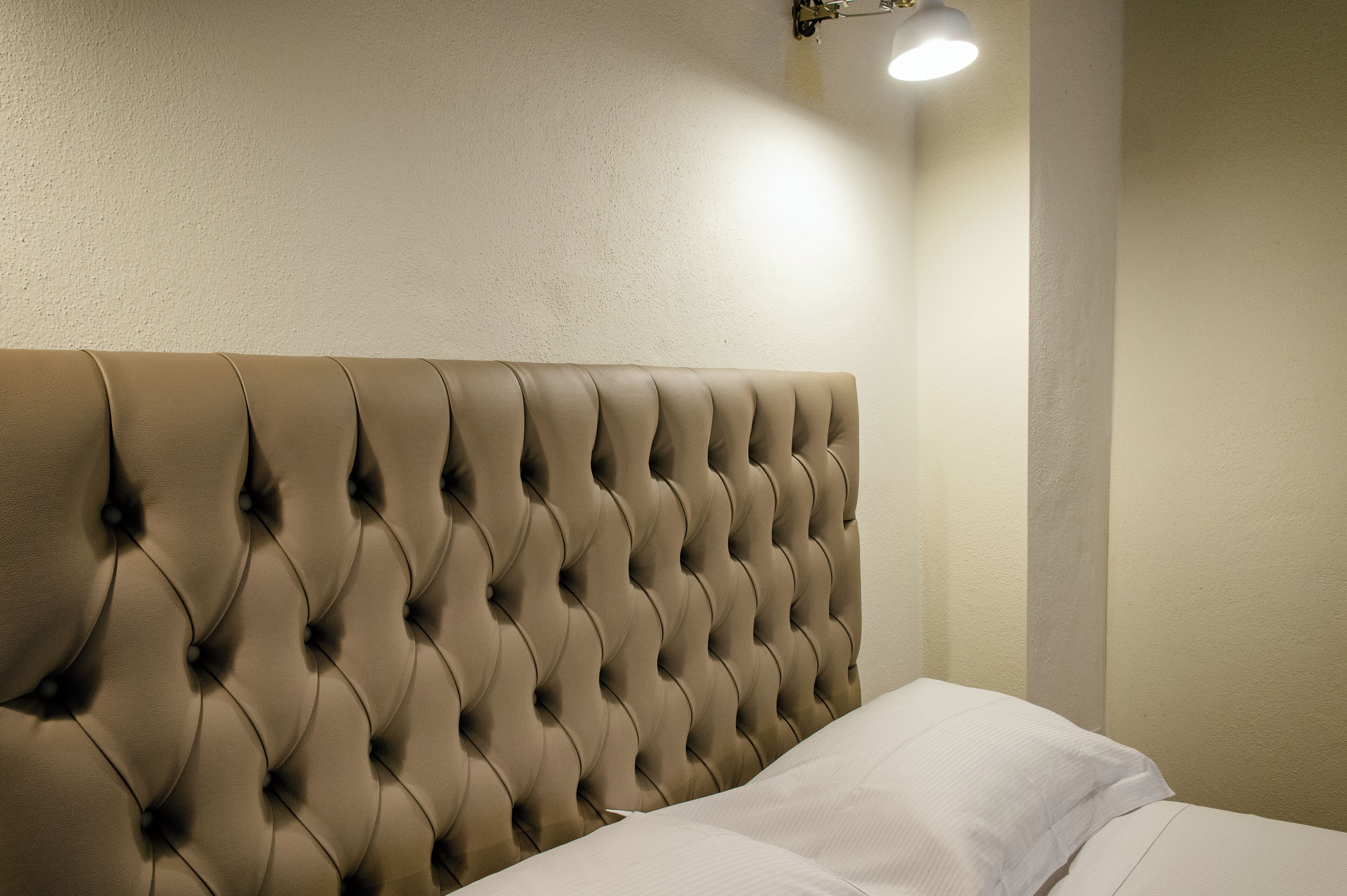 A tufted headboard with a light fixture above it.