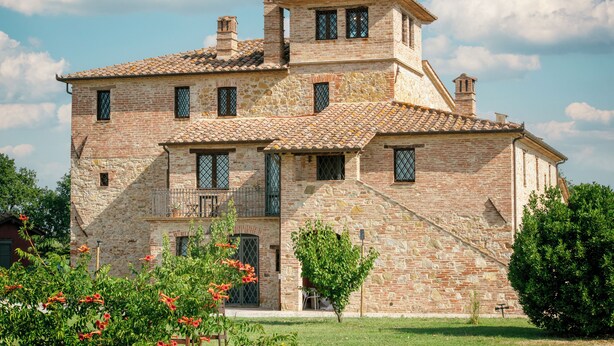 A stone building with multiple windows and a balcony. - Villaluce Wine Agriturismo (Castiglione del Lago)
