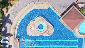 Luchtbeeld van een zwembad met meerdere banen, een centraal rond gedeelte en een apart deel met een rood dak.