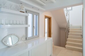 A staircase with a handrail, a white counter with a mirror, and shelves with glassware. - SUNSENSES VILL ARIADNE WITH PRIVATE POOL (Paros)