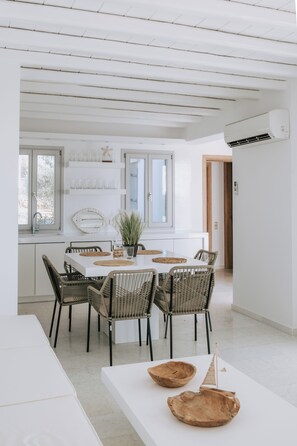 A modern kitchen with white cabinetry, a dining table with chairs, and a potted plant.