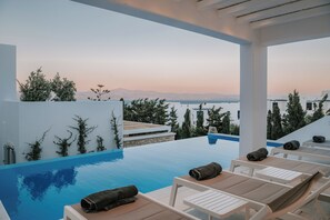Ein unendlicher Pool mit Liegestühlen und Handtüchern mit Blick auf eine gebirgige Landschaft.