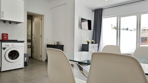 Eine moderne Küche mit Waschmaschine, einem Essbereich mit Stühlen und einem großen Fenster.