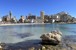 A coastal cityscape with clear waters, a prominent rock formation, and a variety of buildings including high-rise apartments and hotels. - Unique Apartment (La Vila Joiosa)