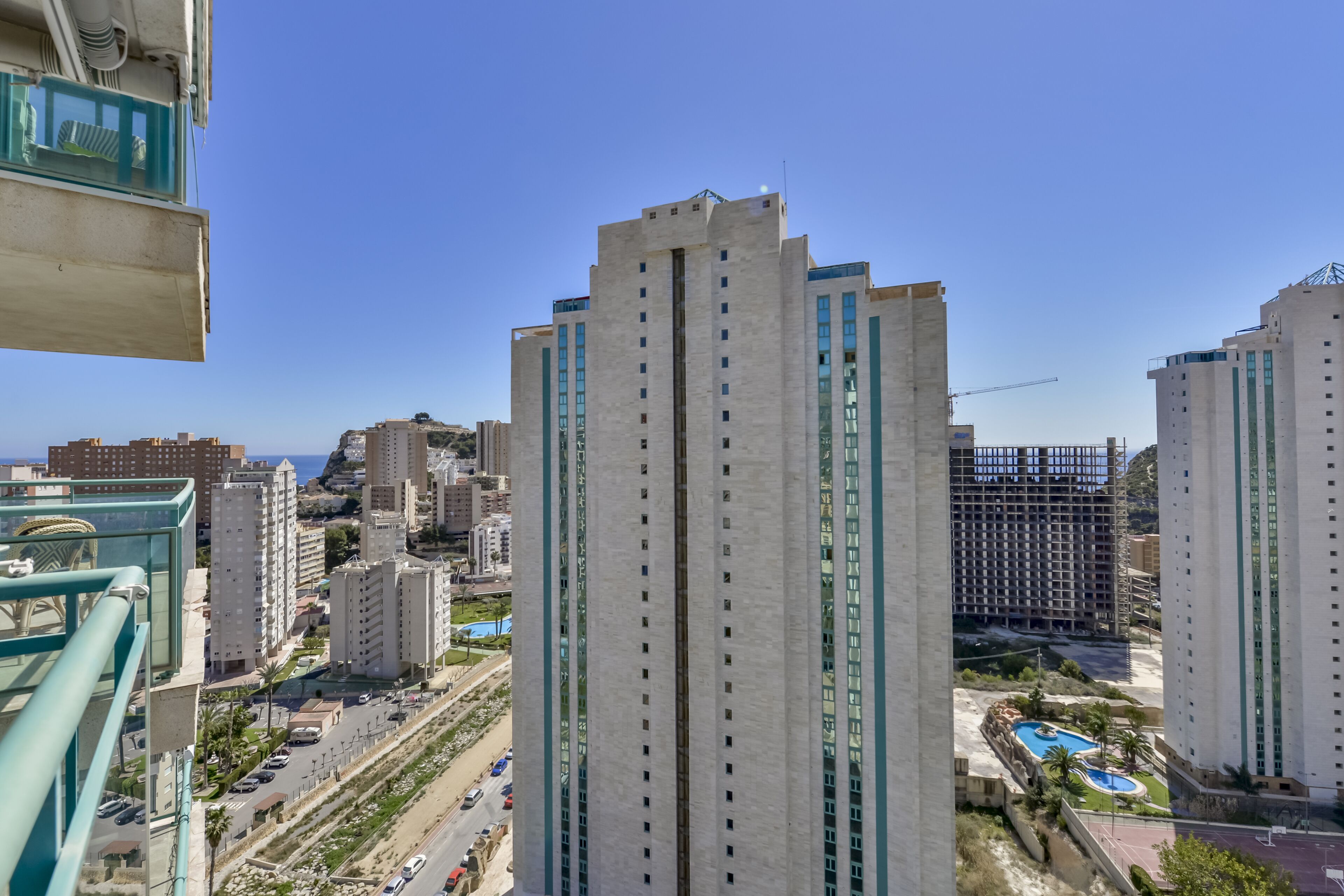 A high-rise building with multiple floors, surrounded by other buildings and a clear sky.