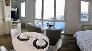 Ein Hotelzimmer mit Essbereich, einem Bett und Blick auf eine Stadtlandschaft.