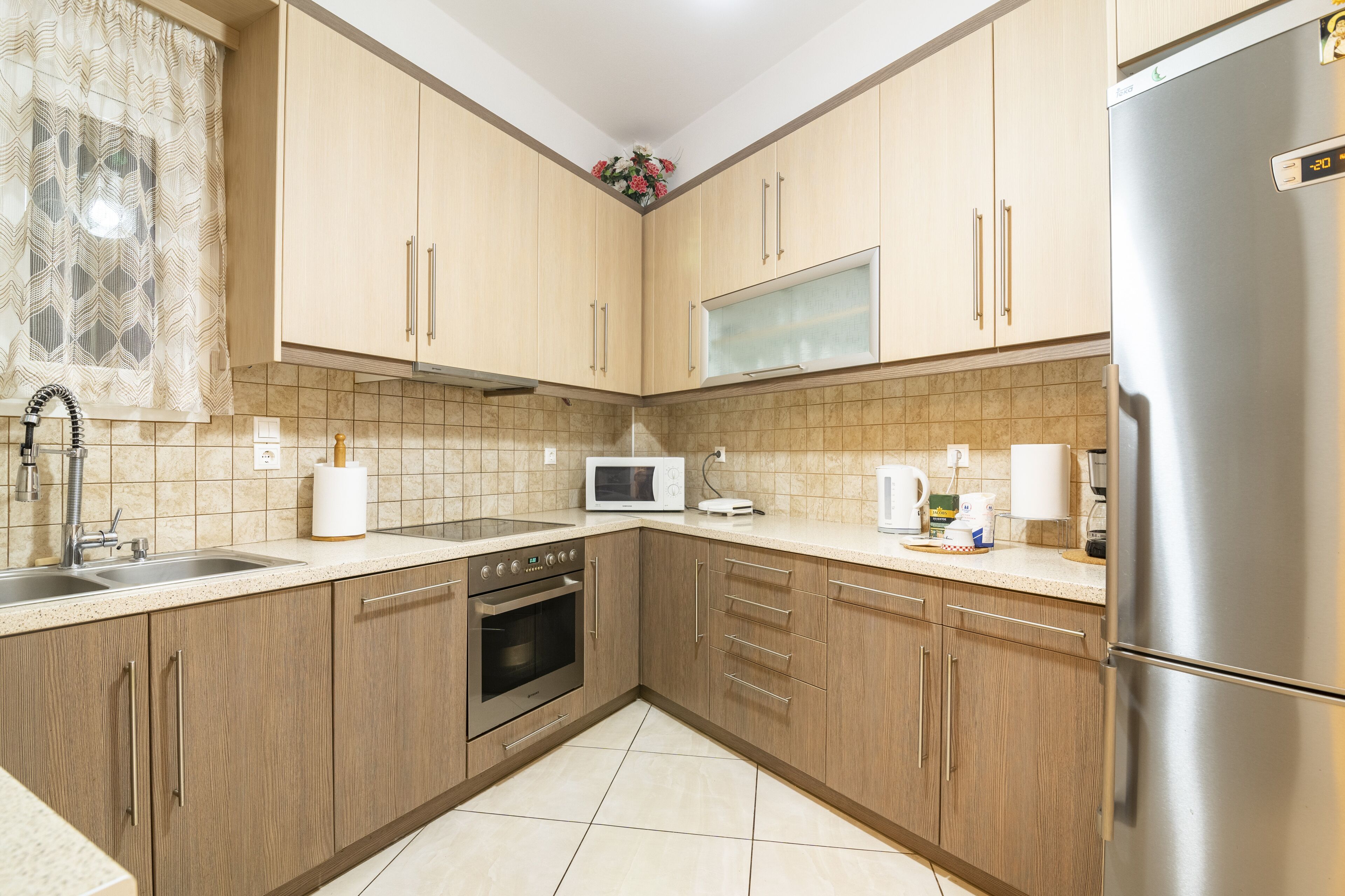 A kitchen with wooden cabinets, a stainless steel refrigerator, a microwave, and a sink.