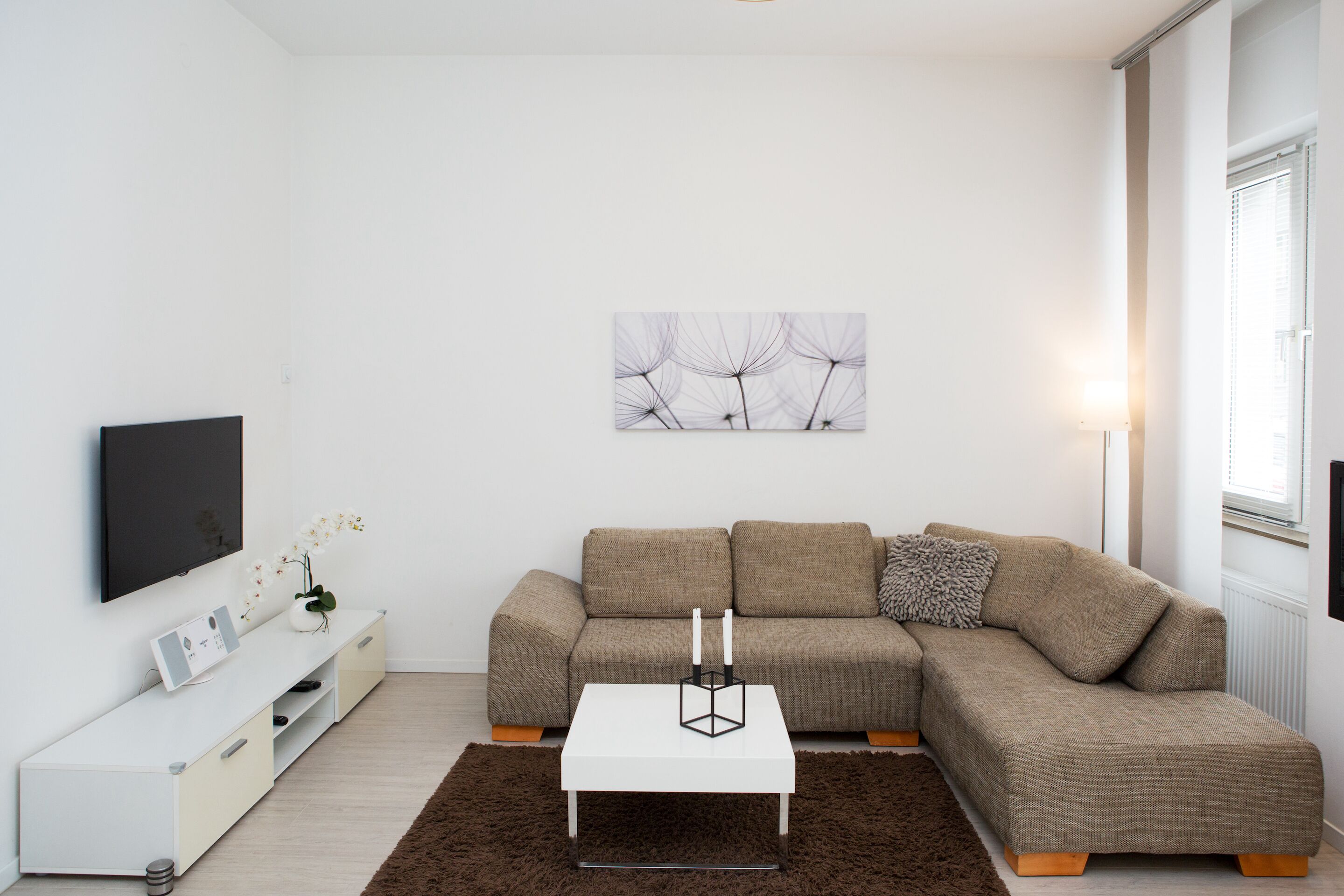 Ein modernes Wohnzimmer mit einem Ecksofa, einem Flachbildfernseher, einem Couchtisch und einer Wanddekoration.