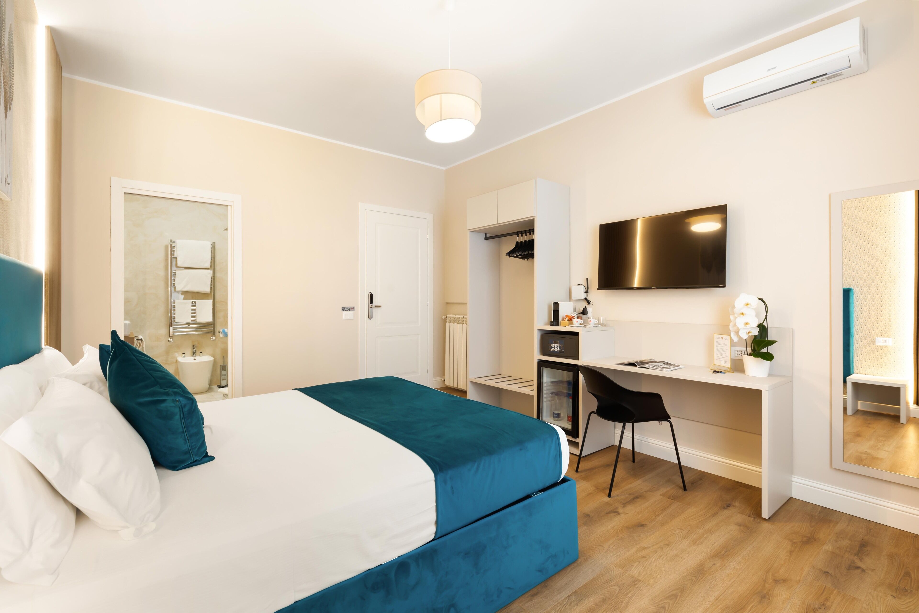A hotel room with a bed, desk, chair, and a television.