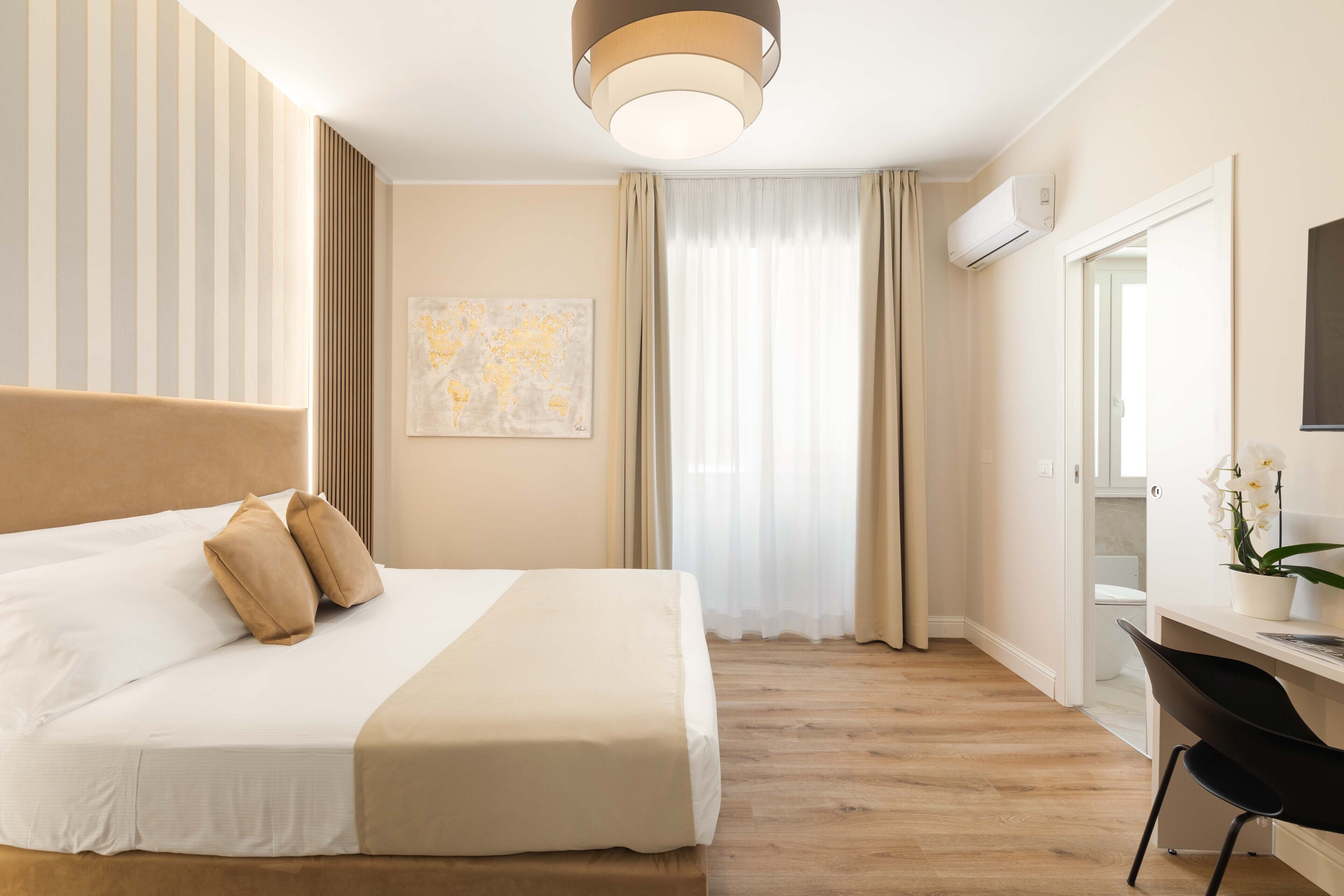 Habitación de hotel con una cama grande, un escritorio con una silla, un mapa del mundo en la pared y un equipo de aire acondicionado.