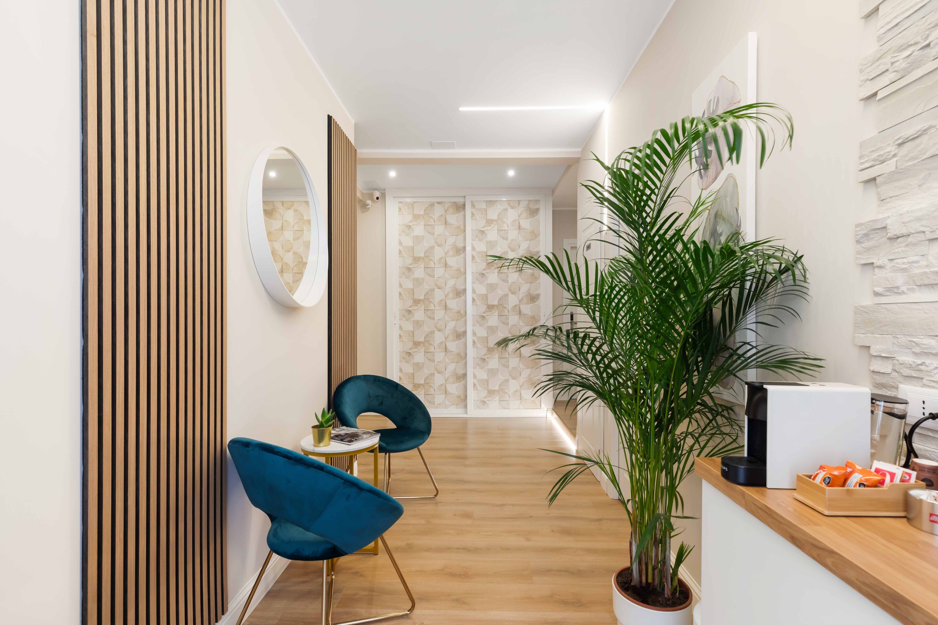 A modern reception area with a wooden reception desk, a potted plant, and a coffee machine.