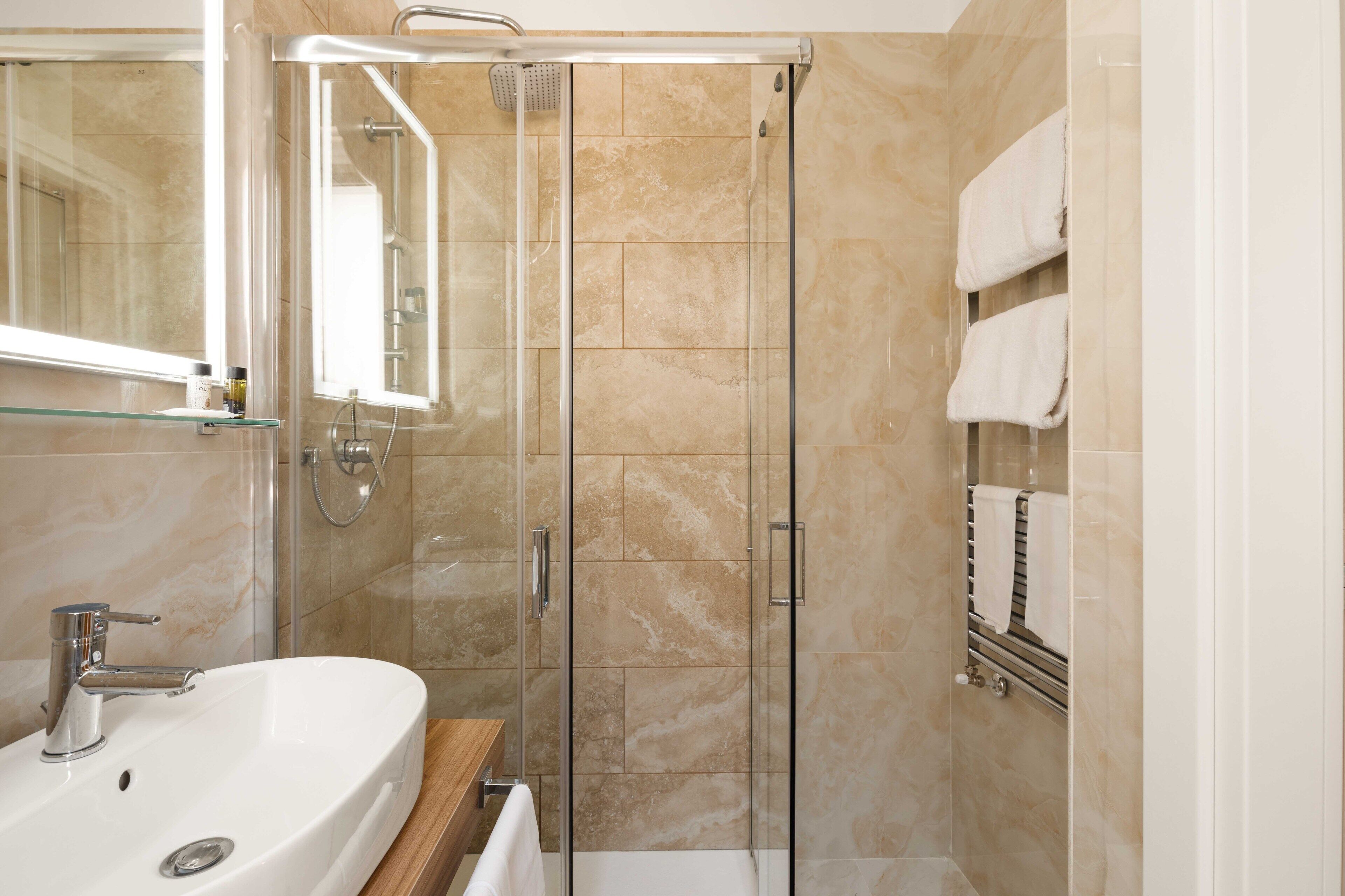 A modern bathroom with a glass-enclosed shower, a white sink, and a mirror.