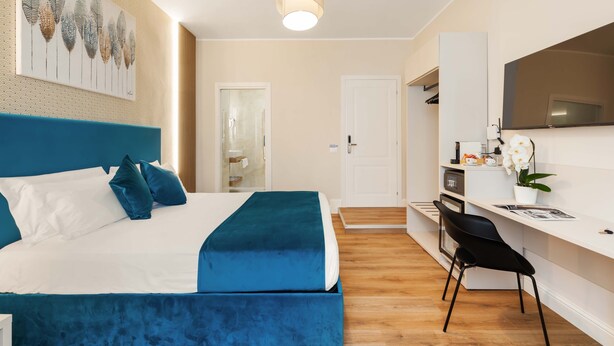 A modern hotel room with a large bed, a desk, and a shower. - AlbaDea Deluxe (Rome)