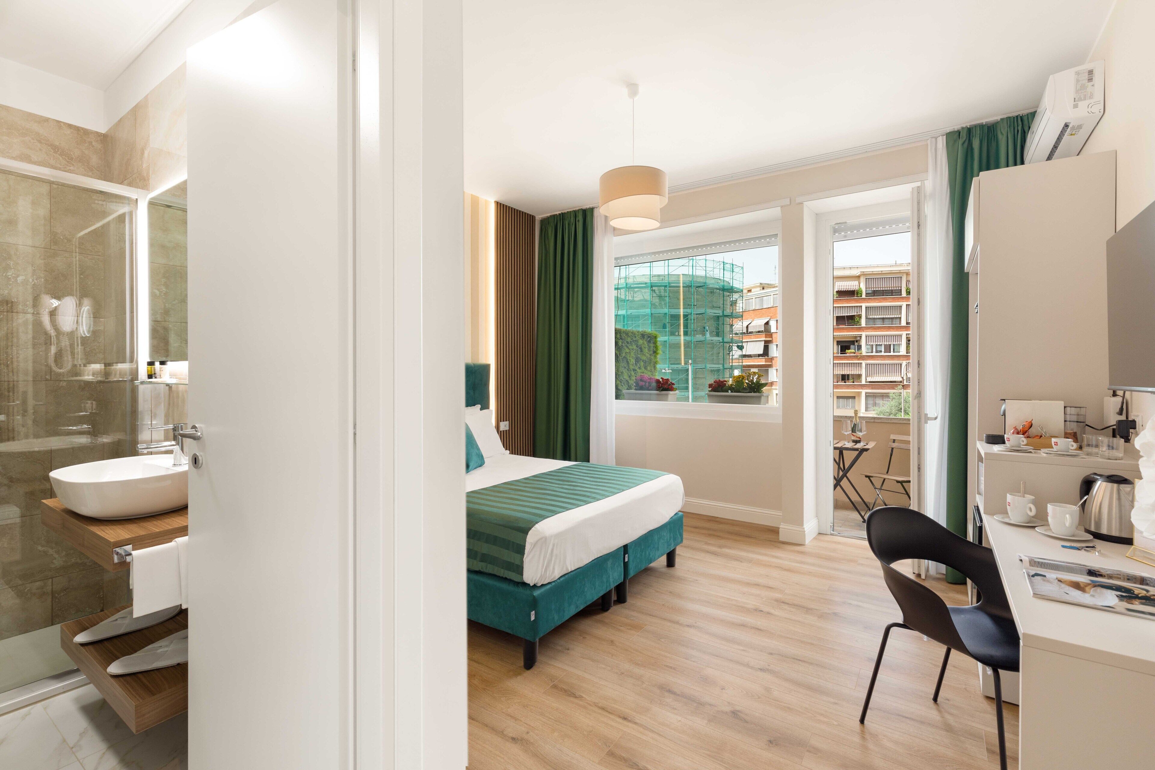 Une chambre d’hôtel moderne dotée d’un grand lit, d’un bureau, d’une salle de bain avec un lavabo et un miroir, et offrant une vue sur la ville grâce à une grande fenêtre.