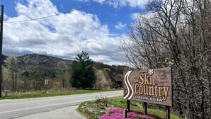 A sign for Ski Country condominiums with a road and mountains in the background. - Dog-Friendly Banner Elk Condo w/ Slope View and Deck (Banner Elk)