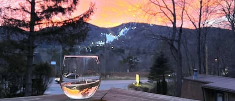 Ein Glas Weißwein auf einer Holzterrasse, über dem hängt eine Glühbirne.