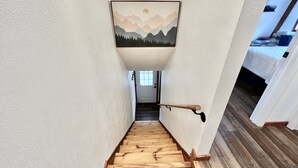 A wooden staircase with a handrail, white walls, and a framed picture of mountains. - Dog-Friendly Banner Elk Condo w/ Slope View and Deck (Banner Elk)