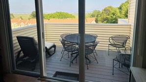 A deck with a table and chairs, overlooking a residential area. - Beautiful Wells Maine Premium Top Floor Condo at Village By The Sea 2 Bed 2 Bath (Wells)