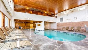 An indoor swimming pool with stone flooring, wooden ceiling, and lounge chairs along the sides. - Beautiful Wells Maine Premium Top Floor Condo at Village By The Sea 2 Bed 2 Bath (Wells)