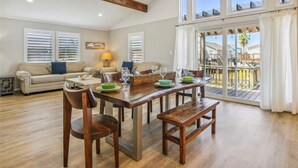 Een eethoek met een houten tafel voor vier personen, een bank en uitzicht op een balkon met een hekwerk.