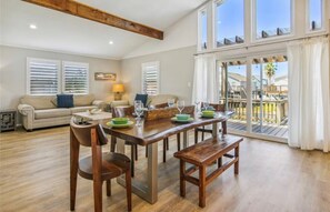 Relax in this spacious living area with a high ceiling and large sliding glass door leading to a balcony with a scenic view.