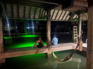Relax on the deck overlooking the water, surrounded by a hammock and a roof structure.